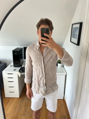 Beige linneskjorta från Riley - Snygg beige skjorta från Riley i 100% linne. Skjortan har klassisk krage, knäppning framtill och långa ärmar. Hör gärna av dig vid frågor!