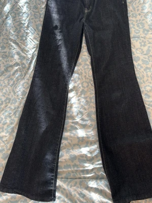 Mörkblå bootcut jeans från GINA TRICOT - Snygga mörkblå bootcut jeans med klassisk femficksdesign och kontrastsömmar. Jeansen har en något utsvängd passform nertill och är perfekta för en trendig och avslappnad look. Materialet är denim med en mjuk känsla.