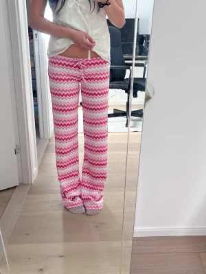 Lågmidjade somriga byxor med zigzag. NY med prislapp - Populära Lågmidjade low waist byxor med rosa och vita zigzag-mönster och rak passform. Byxorna har resår och snörning i midjan för extra komfort. Perfekta för sommaren, våren, utomlands på stranden! Materialet känns mjukt och skönt mot huden. Ny med prislapp