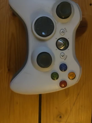 Vit Xbox 360 trådlös handkontroll - Säljer en vit trådlös handkontroll till Xbox 360 från Microsoft. Kontrollen har klassisk ergonomisk form, två analoga spakar, styrkors, samt färgade A, B, X och Y-knappar. Materialet är plast och den drivs med batterier. Perfekt för gaming på Xbox 360.
