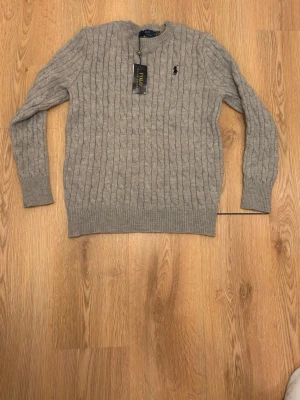 Grå Ralph Lauren cable knit - Säljer denna gråa cable knit från RL, sprillans ny i storlek M som även passar S. Hör av er vid minsta fundering