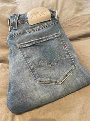 Blå slim fit jeans från Replay - Snygga blå slim fit jeans från Acne Studios med klassisk femficksdesign och ljus tvätt. Jeansen har normal midja och smala ben, perfekta för en trendig och avslappnad look. Tillverkade i mjuk denim med lite stretch för extra komfort.