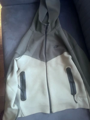 Nike tracksuit (byxor och tröja) i grön och olivgrön  - Nike tracksuit  i tvåfärgad design med grön ovandel och olivgrön nedre del. Dragkedja framtill, två svarta dragkedjefickor och Nike-logga på bröstet. Perfekt för en avslappnad streetwear-look. Bra skick med bästa kvalité och pris 