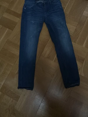 Mörkblå slim Reaplay jeans y12-13 - Snygga mörkblå jeans med rak passform och klassisk femficksdesign. Jeansen har diskreta slitningar och en stilren look som passar till det mesta. Perfekta för dig som gillar en enkel och tidlös stil.