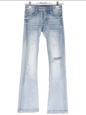 Ljusblå bootcut jeans med slitningar - Snygga ljusblå bootcut jeans med slitningar. Jeansen har klassisk femficksdesign, låg midja och är tillverkade i denim med stretch. De är bootcut och i mycket bra skick. 