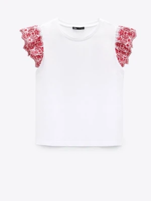 Vit topp med volangärmar från Zara - Superfin vit topp från Zara med korta volangärmar i rött blommigt spetsmönster. Perfekt för dig som vill ha en söt och trendig look med det lilla extra på ärmarna. Tillverkad i mjuk bomull för skön känsla.