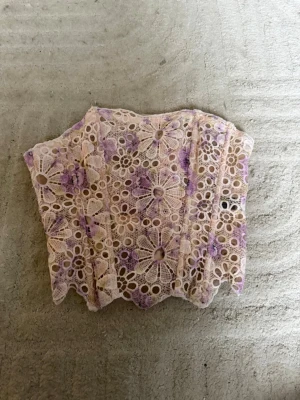 Ljuslila spetskorsett med blommönster - Säljer en fin korsett i ljusbeige spets med lila blommönster och vita snörningar bak. Perfekt för dig som vill ha något unikt och snyggt i garderoben 💜💕