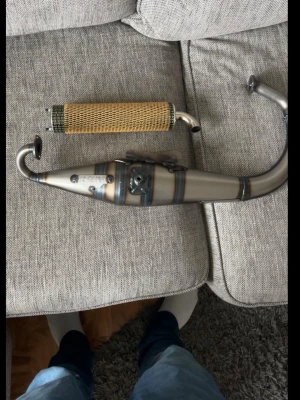 Avgassystem till moped - Säljer ett avgassystem till moped med snyggt svetsad finish i metall och ljuddämpare med guldigt nät runt om. Passar dig som vill uppgradera din moppe med en cool och sportig look.