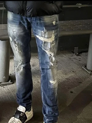 Blå slitna jeans från Replay  - Säljer ett par blå jeans från Replay med slitna detaljer och trasiga partier. Jeansen har en slim passform och klassisk femficksdesign. Perfekta för dig som gillar en edgy streetstil.