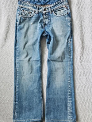 Ljusblå vintagejeans Jack & Jones L90 - Snygga ljusblå vintagejeans från Jack & Jones med raka ben och klassisk femficksmodell. Jeansen har slitna detaljer och en avslappnad passform. Perfekta för en casual och trendig look.