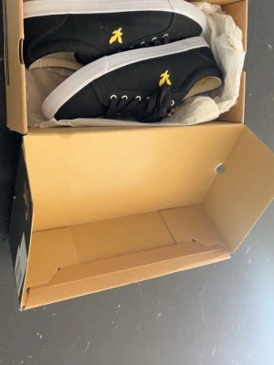 Svarta Lyle & Scott sneakers - Svarta sneakers från Lyle & Scott med klassisk låg profil, vita sulor och svarta skosnören. Skorna har den ikoniska gula örnloggan broderad på sidan och insidan. Ovandelen är i textil och sulan i gummi. Perfekta för en clean och stilren look. Storlek 43. Pris kan diskuteras!