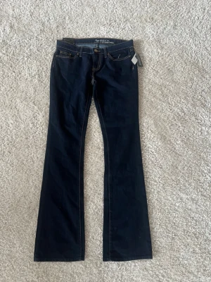Mörkblå bootcut jeans från GAP - Snygga mörkblå bootcut jeans från GAP  som är oanvända med lappar kvar. Jeansen har låg midja och utsvängda ben, perfekt för en trendig och avslappnad look. Midja platt: 40cm och innerbenslängd: 86cm