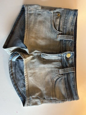 Gråblå jeansshorts från Cheap Monday - Snygga oanvända gråblå jeansshorts från Cheap Monday med klassisk femficksdesign och en cool grön logga bak. Shortsen har bälteshällor, knapp och dragkedja framtill. Shortsen är helt oanvända och är i storlek 26 som ungefär motsvarar XS!💗💗