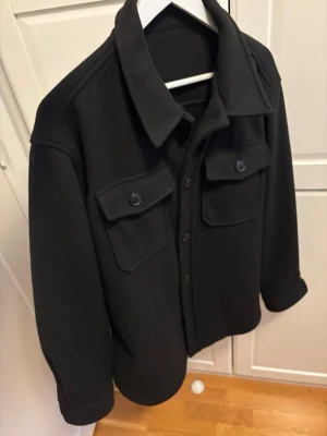 Svart overshirt - En riktig schysst och enkel Overshirt i svart färg. Priset är förhandlingsbart så det är bara att buda på.                                                                            (Reguler fit i passform!)