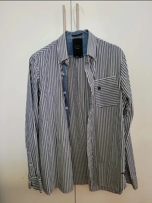 Randig skjorta från G-Star RAW - Snygg skjorta från G-Star RAW med vertikala svarta och vita ränder. Knappt använd, mycket gott skick.