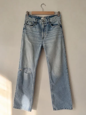 Jeans - Jeans, ljusblå med hål i ena knät, högmidjade med knappar (se bild 3). Kontakta för mer info/fler bilder. 