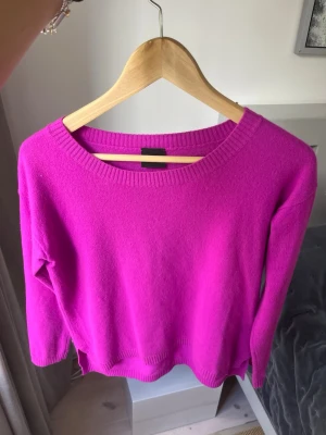 Klarrosa stickad tröja KASHMIR - En snygg klarrosa stickad tröja med rund halsringning och långa ärmar. Tröjan har ribbade muddar vid hals, ärmslut och nederkant. Perfekt för dig som vill ha en färgklick i garderoben.