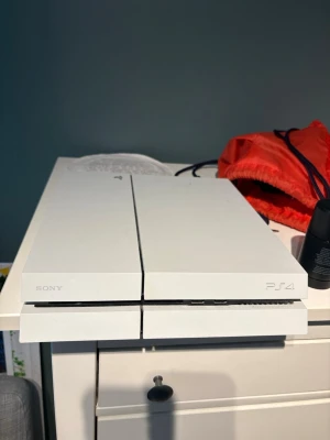 Playstation 4 - Vit Sony Playstation 4 som fungerar utmärkt. De enda som kan vara störande är att den låter ganska mycket, de som skulle behövas är att man rengör fläkten.  Handkontroll + kablar ingår   Vid snabbaffär kan jag även skicka med några spel.