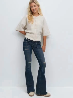 Mörkblå bootcut jeans med slitningar - Snygga mörkblå bootcut jeans med lätt slitna detaljer på låren och knäna. Jeansen har klassisk femficksdesign, normal midja och utsvängda ben. Perfekta för en trendig och avslappnad look.