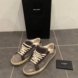 Gråa Saint Laurent skor - Säljer ett par gråa saint Laurent skor. Dom är i storlek 41 men passar som 42. Inga defekter, box och dustbag medföljer. Skriv om du har några funderingar.