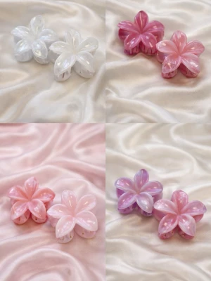 Blommiga hårklämmor i pastell - Säljer söta hårklämmor formade som blommor i olika pastellfärger: vitt, rosa, lila och ljusrosa. Klämmorna har en glansig, pärlemorliknande yta och är perfekta för att piffa upp frisyren. Materialet är plast.Skriv privat för färg!