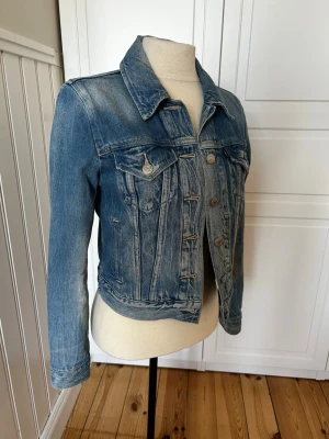 Klassisk blå jeansjacka från Levi's - Snygg blå jeansjacka från Levi's med klassisk passform, bröstfickor med knappar och slitna detaljer. Jackan har knappstängning framtill och en tidlös look som funkar till allt. Perfekt för dig som gillar streetstyle och denim.