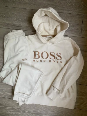 Set Hugo boss luvtröja och byxa - Set från Hugo Boss i creme. Luvtröja är i strl S och byxor i xs, passar mig som har s. Mycket fint skick, det som finns att anmärka på är att en bokstav fattas på trycket längst ner på ärmen. Inget man direkt lägger märke till.