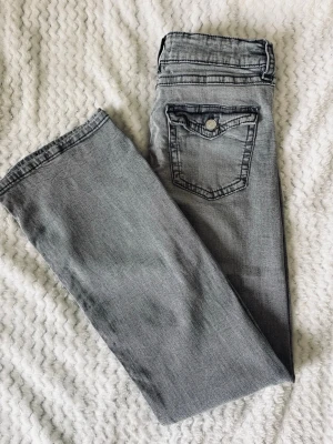 Gråa lowwaisted bootcut jeans - Gråa Gina Young low-waisted jeans med bootcut. Jättesnygga och stretchiga🤩🤩Är i storlek 170 men passar som S. Anvönda några gånger men är i jättebra skick!! Skriv gärna vid frågor och pris kan diskuteras🤗🤗