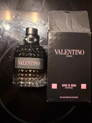 Valentino Uomo Born In Roma Intense - Lyxig parfym från Valentino, Uomo Born In Roma Intense. Flaskan är svart med diamantmönster och har en elegant svart etikett. Kommer i en svart kartong med rosa detaljer. Doften är Eau de Parfum Intense och flaskan rymmer 100 ml. Säljs med kvitto