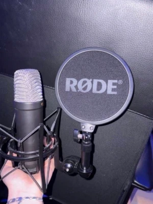 RØDE mikrofon med popfilter - Säljer en svart RØDE mikrofon med tillhörande popfilter. Mikrofonen har en klassisk cylinderform och är monterad i en stötdämpande hållare. Perfekt för inspelning av podd, musik eller streaming.
