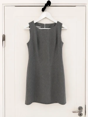 Grå ärmlös klänning från Totême - Stilren grå klänning från Totême i klassisk rak modell. Klänningen är ärmlös med rund halsringning och slät yta, perfekt för en minimalistisk look. Tillverkad i ett mjukt material som ger en bekväm passform.