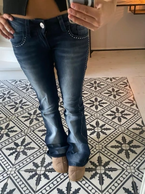Blå bootcut jeans med nitar - Säljer dessa jeans då de inte kommer till användning, de är helt oanvända. Kontakta för fler bilder. 