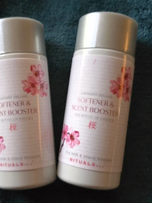 Rituals Sakura doftförstärkare tvätt. 2 × 75 ml - Två flaskor Rituals Laundry Deluxe Softener & Scent Booster i doften The Ritual of Sakura. Innehåller risextrakt och körsbärsblomma. Flaskorna är vita med rosa blommor och silverfärgade lock. Perfekt för att ge tvätten en fräsch och blommig doft.