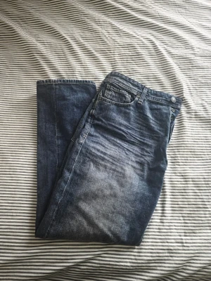 Blå relaxed fit jeans Chris 32/34 - Säljer ett par blå jeans i relaxed fit, modell Chris. Jeansen har klassisk femficksdesign, normalhög midja och snygg tvättad look med slitningar framtill. Perfekta för en avslappnad stil och passar till det mesta. Materialet är klassisk denim.