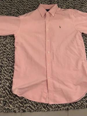 Rosa skjorta från Ralph Lauren - Klassisk rosa skjorta från Ralph lauren. Använd ett fåtal gånger så i princip ny skick. Stl 18 vilket motsvarar small ungefär. Säljer för att jag har vuxit ur den. Skriv för fler bilder. Nypris 1599 kronor. 
