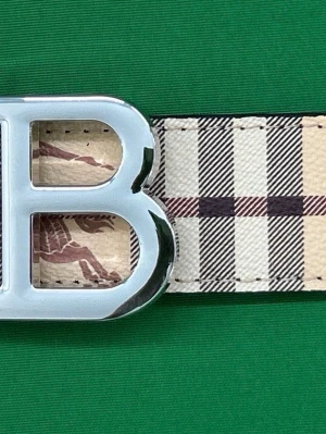 Rutig Burberry skärp med B-spänne - Snyggt skärp från Burberry med klassiskt rutigt mönster i beige, svart och rött. Skärpet har ett stort, silverfärgat B-spänne och är gjort i skinn. Perfekt för att lyfta vilken outfit som helst.