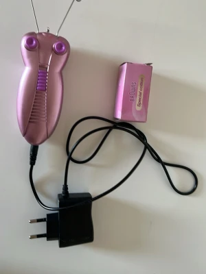 Rosa BaLunis ansiktstrådmaskin - Elektrisk ansiktstrådmaskin vet inte vart den är ifrån men är i metallicrosa plast med lila detaljer. Kommer med strömadapter och special cotton-tråd. Perfekt för hårborttagning i ansiktet och ger en slät finish. Smidig att använda hemma.