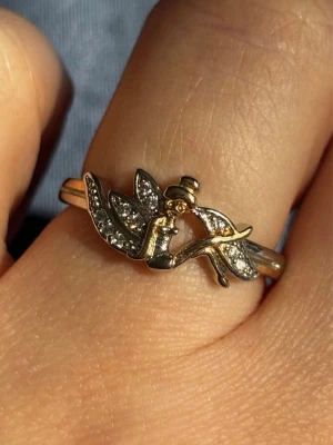  Ring med Älva och Stenar i Sterling Silver - Unik Ring med en detaljrik älva som motiv. Älvan har vingar dekorerade med små gnistrande stenar som ger ringen en magisk känsla. Perfekt för dig som gillar sagoinspirerade accessoarer och vill sticka ut med något speciellt. Har stämpel som syns på bild. I fint skick.