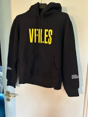 Svart VFILES Purpose Tour hoodie - Säljer en svart hoodie från VFILES med stor gul logga framtill och Purpose Tour-tryck i gult på ryggen. Stockholm står tryckt under loggan bak. Hoodien har huva med dragsko och magficka. Tryck även på ärmarna. Perfekt för dig som gillar streetwear och konsertmerch. Justin Bieber. Helt ny.