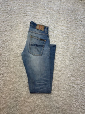 Ljusblå Nudie Grim Tim  - Skick: 8/10, använda med snygga lagningar| Storlek W28 L32| Modell: Grim Tim vilket är straight/slimfit| Gåva ingår vid köp!