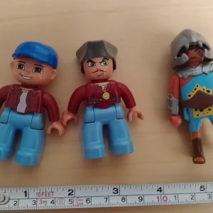 Tre Playmobil-figurer, olika stilar - Säljer tre Playmobil-figurer: två med blå byxor och röda jackor, en med blå keps och en med grå hatt, samt en riddare med hjälm, rustning och detaljerad sköld. Perfekta till samlingen eller lek. Alla är ca 7 cm höga.