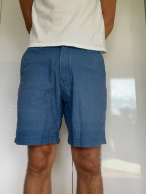 Blå linneshorts  - Blå shorts från These Glory Days tillverkad i 55% linne och 45% bomull. Strl. Modellen är 178 cm och väger 77 kg. Hör gärna av dig vid frågor!