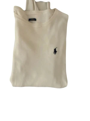 Beige stickad tröja från Polo Ralph Lauren - Snygg beige stickad tröja från Polo Ralph Lauren i slim fit-modell. Tillverkad av mjuk pima bomull och har den klassiska broderade loggan på bröstet. Nypris 2400 kronor, lappen ramlat av, därav rabatterat pris. Storlek M