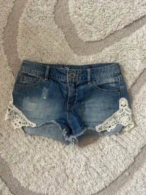 Blå jeansshorts med spetsdetaljer - Säljer mina absoluta favoritshorts med så fina detaljer på sidorna!!! Supersnygga nu till sommaren🥹🥹🥹 strlk 152 men skulle säga att dom passar xxs. Pris kan diskuteras och skriv om du har någon fråga!
