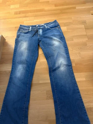 Blå bootcut jeans från Only - Säljer ett par blå bootcut jeans från Only med slitningar på låren och klassisk femficksmodell. Jeansen har en lätt utsvängd passform nedtill och är gjorda i denim. Perfekta för dig som gillar retrostil och vill ha ett par snygga jeans med unik look. Jag skulle säga storlek M/L 