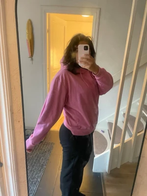 Rosa hoodie med huva - En enkel och snygg rosa hoodie med huva och dragsko. Hoodien har en avslappnad passform och ribbade muddar vid ärmslut och nederkant. Perfekt för en chill och bekväm stil. Materialet känns mjukt och skönt mot huden.