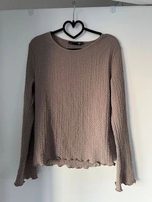 Beige långärmad topp med volangkant - Säljer en beige långärmad topp, crinklat tyg och volangkant vid ärmslut och nederkant. 