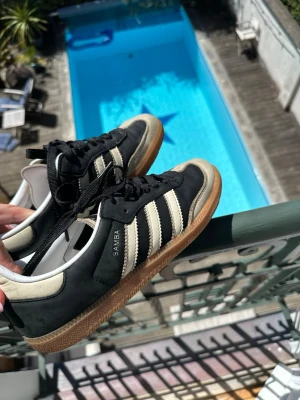 Adidas Samba svart/vit sneakers - Klassiska Adidas Samba sneakers i svart mocka och läder med beiga detaljer och gummisula. Skorna är unika och supersnygga till sommaren. 🍓