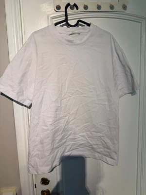 Vit basic t-shirt i bomull - En klassisk vit t-shirt med rund hals och korta ärmar. Tillverkad i mjuk bomull, perfekt för en clean och enkel stil. Passar till allt och är ett måste i garderoben.