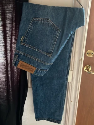 Blå jeans från Woodbird - Säljer ett par snygga blå jeans från Woodbird i modellen Doc Blooke. Jeansen har en klassisk femficksdesign, rak passform och är i färgen Blue Stone. Perfekta för dig som gillar en tidlös och avslappnad stil.